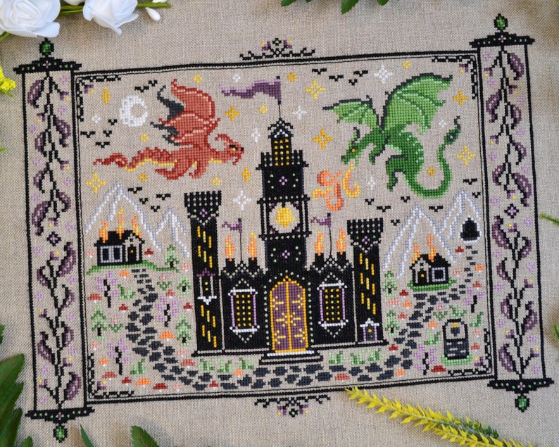 Castles & Dragons cross stitch pattern finish. Features flying fire dragon and a large castle on a scroll.