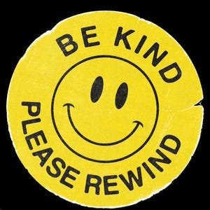 Puede incluir: Una pegatina amarilla circular con una carita sonriente y las frases "BE KIND" y "PLEASE REWIND" en texto negro. La pegatina tiene un aspecto envejecido y vintage sobre un fondo negro.