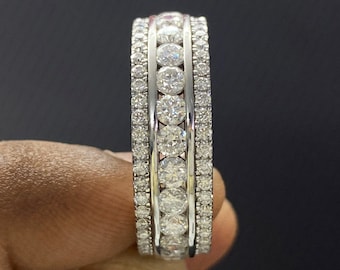 May include: A silver band ring with multiple rows of round, clear diamonds.