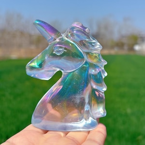 May include: A clear iridescent glass unicorn head sculpture. The sculpture has a rainbow sheen and is a popular decor item for fantasy and mythical creature enthusiasts.