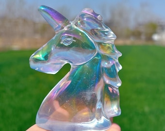May include: A clear iridescent glass unicorn head sculpture. The sculpture has a rainbow sheen and is a popular decor item for fantasy and mythical creature enthusiasts.