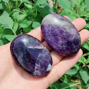 May include: Two smooth, oval-shaped amethyst stones with purple and white swirls. The stones are polished and have a glossy finish.