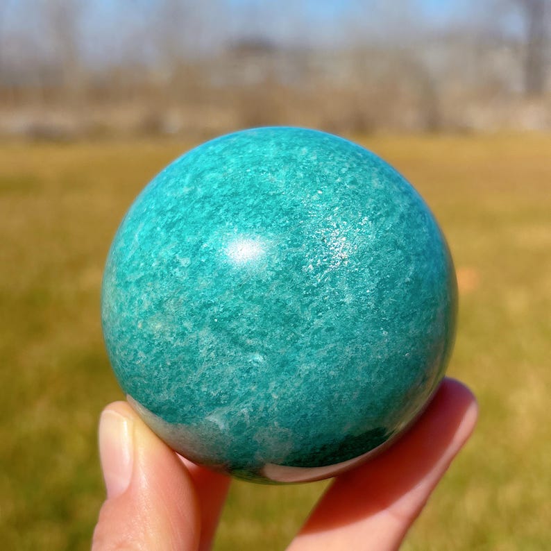 Puede incluir: Una esfera de aventurina verde lisa. La esfera est&aacute; pulida y tiene un color verde claro con vetas blancas.