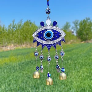 May include: A blue and silver evil eye wind chime with bells and charms. The evil eye is a symbol of protection against negative energy.