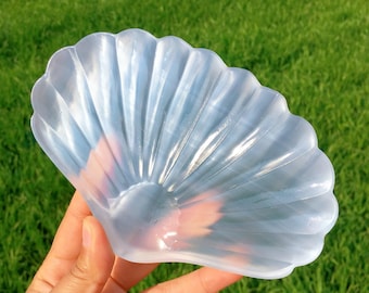 以下が含まれることがあります： セレン石の結晶で作られた、透明で虹色の貝殻の形をした皿。皿は滑らかで、繊細な波状の質感があります。