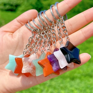 Può includere: Un set di otto portachiavi di cristallo a forma di stella. I portachiavi sono realizzati con diversi tipi di cristalli, tra cui ametista, quarzo rosa, diaspro rosso, aventurina verde e ossidiana nera. Ogni portachiavi è attaccato a una catena d'argento e un anello portachiavi d'argento.