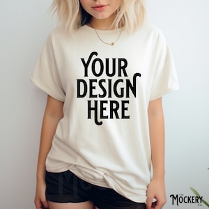 May include: A white t-shirt with the text "YOUR DESIGN HERE" printed in black on the front.