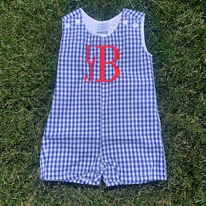 Peut inclure: Combinaison bébé en gingham bleu et blanc avec les initiales "JB" brodées en rouge.
