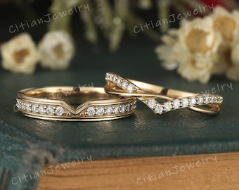 May include: Two gold wedding rings with small, clear gemstones. One ring has a V-shaped design with gemstones, and the other has a crisscross design with gemstones. The rings are on a dark green surface with the text "Citian Jewelry".