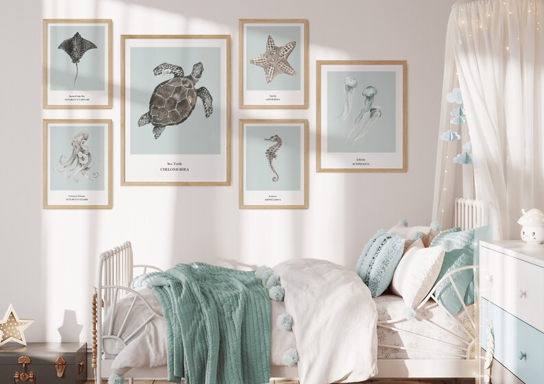 K&ouml;nnte beinhalten: Ein wei&szlig;es Bett mit einer hellblauen Decke und Kissen in einem Schlafzimmer mit einer wei&szlig;en Wand und sechs gerahmten Drucken von Meerestieren. Die Drucke zeigen eine Meeresschildkr&ouml;te, einen Seestern, eine Qualle, einen Oktopus, einen Rochen und ein Seepferdchen.