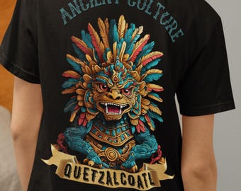 May include: A black t-shirt featuring a graphic print on the back. The design displays a stylized creature with a feathered headdress in shades of blue, gold, and red, with the text "ANCIENT CULTURE" above and "QUETZALCOATL" on a banner below.