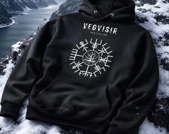 May include: A black hooded sweatshirt featuring a white graphic print on the chest. The design includes the text VEGVISIR PROTECTION above a circular runic compass symbol with a tree illustration at its centre. The hoodie has long sleeves.