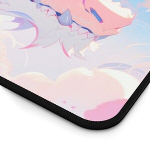 May include: A pink and white mousepad with a cartoon dragon design. The dragon has blue eyes and a pink and white body. The background is a light blue with white clouds.