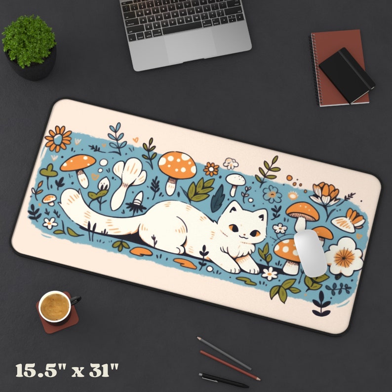 May include: A cream-colored mousepad with a whimsical illustration of a white cat lounging among orange mushrooms and flowers. The mousepad measures 15.5" x 31" and has a black border. A computer mouse rests on the pad.