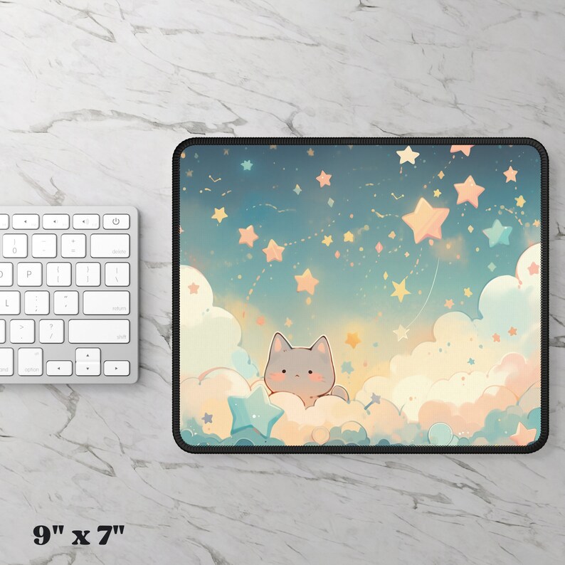 Puede incluir: Un gato gris con mejillas rosadas se sienta en una nube con una estrella azul frente a &eacute;l. El fondo es un cielo azul con muchas estrellas blancas y amarillas. La alfombrilla de rat&oacute;n mide 9 pulgadas por 7 pulgadas.