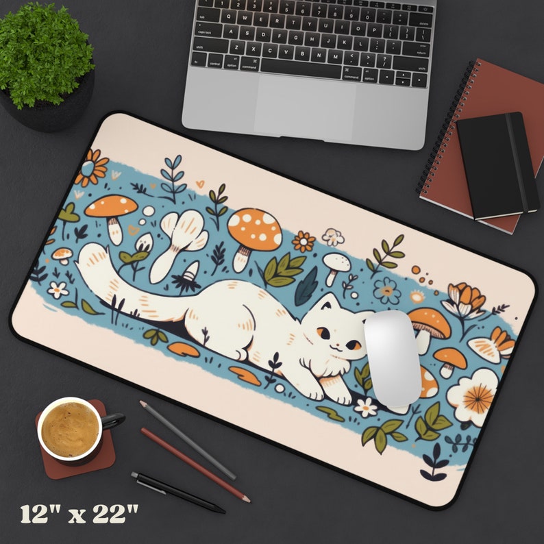 May include: A rectangular mouse pad with a whimsical design featuring a white cat lounging amidst mushrooms and flowers. The pad measures 12 inches by 22 inches. The design includes a blue stripe and a beige background.