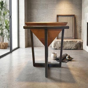May include: A side table featuring a dark metal frame with a triangular wooden base and a flat square top. The structure consists of four vertical metal legs that support the inverted pyramid-shaped wooden section, creating a geometric silhouette.