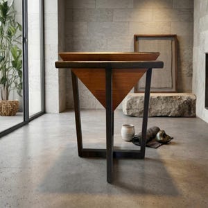 May include: A modern wooden side table with a geometric design. The table features a dark metal frame and a triangular wooden panel. The top surface is a light brown color. The table is 30 inches tall.