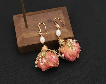 May include: A pair of gold earrings with pink dried flower buds and white pearl accents.