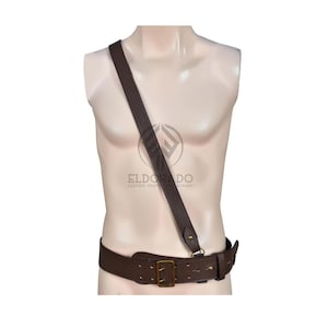 May include: A brown leather belt with a matching shoulder strap. The belt has a rectangular brass buckle and multiple holes for adjustment. The strap is attached to the belt with a brass fitting. The logo "ELDORADO LEATHER CRAFT" is visible.