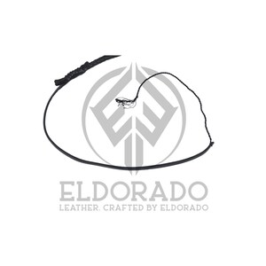 K&ouml;nnte beinhalten: Eine schwarze Lederpeitsche mit geflochtenem Griff und langer, d&uuml;nner Peitschenschnur. Die Peitsche wird vor einem wei&szlig;en Hintergrund mit dem Text "ELDORADO LEATHER. CRAFTED BY ELDORADO" gezeigt.