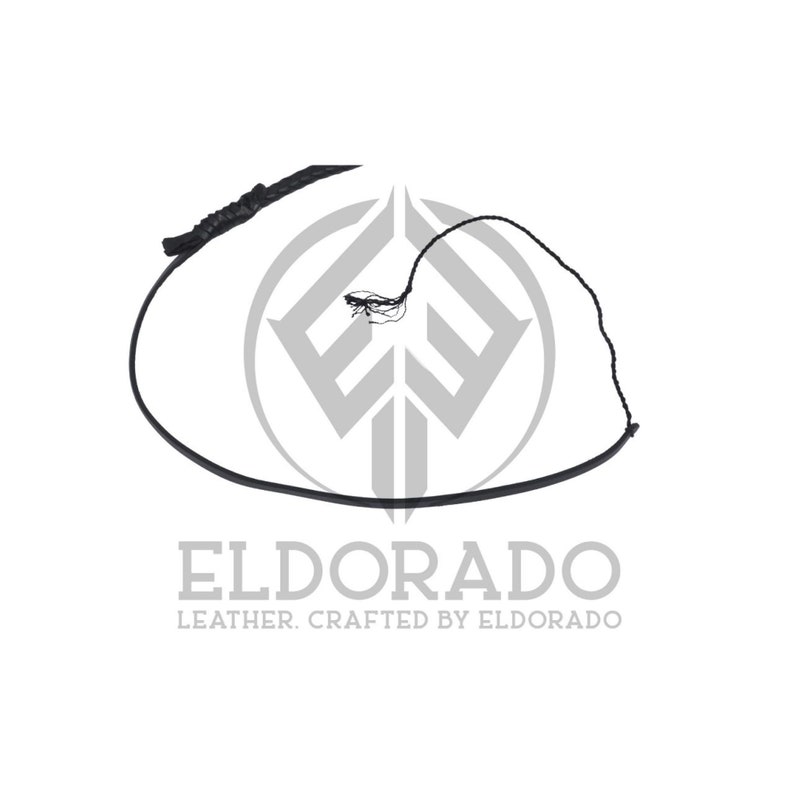 K&ouml;nnte beinhalten: Eine schwarze Lederpeitsche mit geflochtenem Griff und langer, d&uuml;nner Peitschenschnur. Die Peitsche wird vor einem wei&szlig;en Hintergrund mit dem Text "ELDORADO LEATHER. CRAFTED BY ELDORADO" gezeigt.