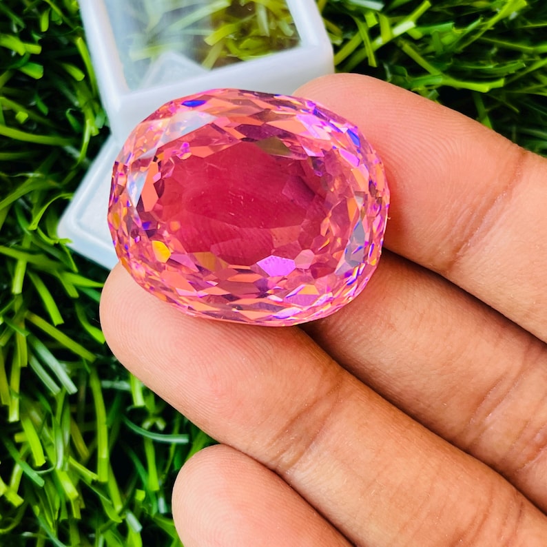 Peut inclure: Une grande pierre pr&eacute;cieuse rose de forme ovale avec une taille facet&eacute;e. La pierre pr&eacute;cieuse est claire et a une l&eacute;g&egrave;re teinte violette.