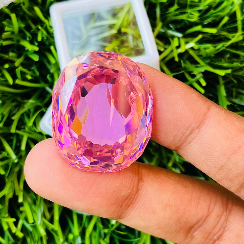 Peut inclure: Une grande pierre pr&eacute;cieuse rose facet&eacute;e avec un haut poli. La pierre pr&eacute;cieuse est de forme ovale et a un &eacute;clat brillant et iridescent.
