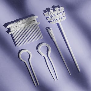 May include: A collection of white hair accessories, including combs and hair sticks, arranged on a lavender surface. The accessories feature intricate designs and varying shapes, with a focus on decorative elements.