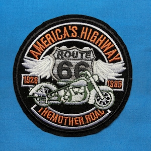 Puede incluir: Parche bordado circular con una motocicleta y el texto "America's Highway The Mother Road Route 66". El parche tiene un borde negro con letras naranjas y blancas, y los años 1926 y 1985.