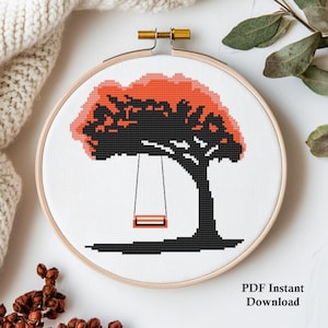 May include: Cross stitch pattern featuring a black silhouette of a tree with a red and orange canopy and a swing hanging from a branch. The pattern is in a white embroidery hoop.