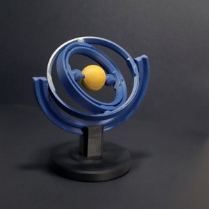 May include: A blue and yellow abstract sculpture with a circular design. The sculpture is made of metal and has a smooth, polished finish.