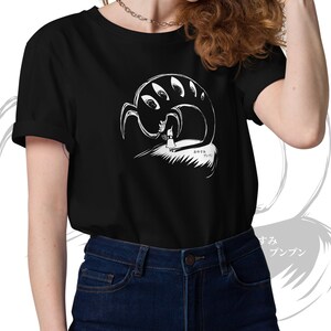 May include: Black t-shirt featuring a white graphic of a creature with multiple eyes and a figure. The design includes Japanese text. The shirt is a short-sleeved crew neck.