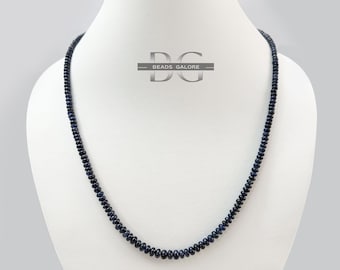 May include: A dark blue sapphire bead necklace on a white mannequin. The necklace is made of small, round beads and is approximately 18 inches long.