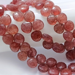 May include: A strand of faceted, reddish-brown gemstone beads. The beads are round and have a slightly irregular shape.