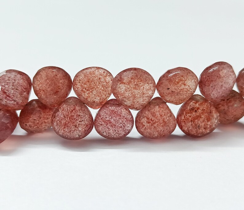 May include: A strand of translucent red gemstone beads with a faceted, teardrop shape.