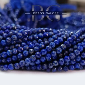 May include: A strand of deep blue lapis lazuli beads, each bead is faceted and round, the beads are strung together to form a long strand.