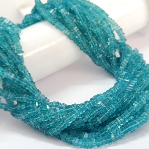 Op de afbeelding: Een bundel kleine, vierkant geslepen, lichtblauwe edelstenen. De edelstenen zijn aan elkaar geregen en vormen een dikke, gedraaide streng. De kleur is een helder, helder turquoise en de stenen lijken gepolijst.
