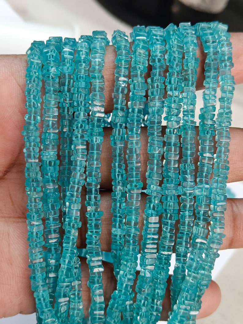 Op de afbeelding: Meerdere strengen lichtblauwe, vierkant geslepen kralen. De kralen zijn doorschijnend en geregen, waardoor een watervaleffect ontstaat. Deze kralen zijn ongeveer 3 mm groot en perfect voor het maken van sieraden.