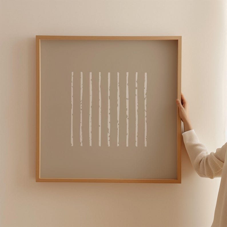 May include: A square wall art piece featuring a light brown background with a series of eleven vertical white lines. The lines have a textured, irregular appearance and are enclosed within a simple, light-toned wooden frame.