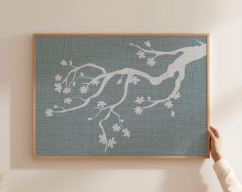 May include: A rectangular wall art piece featuring a white silhouette of a flowering tree branch against a textured, muted blue-gray background. The artwork is encased in a thin, light-toned wooden frame, displaying a botanical motif.