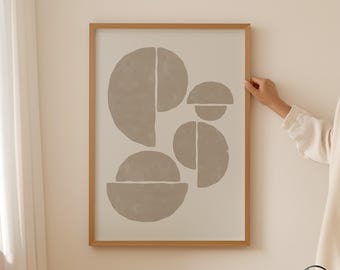 May include: A framed wall art print featuring a light beige background with abstract taupe geometric shapes, including circles and semi-circles. The wooden frame is light brown. The bottom right corner displays the text SHIBUI PRINT STUDIO.