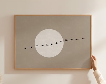 May include: A rectangular wall art print in a light wooden frame featuring a taupe background with a large, pale off-white circular moon shape in the centre. A horizontal line of small, black bird silhouettes flies across the moon and background.