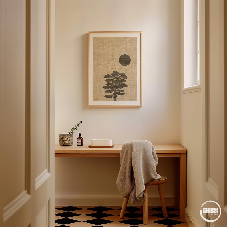 K&ouml;nnte beinhalten: Ein gerahmter, rechteckiger Wandkunstdruck mit der Silhouette eines dunkelgrauen Baumes und einem einfarbigen dunkelgrauen Kreis auf strukturiertem beigem Hintergrund. Der Druck h&auml;ngt an einer hellen Wand &uuml;ber einem Schreibtisch aus Holz.