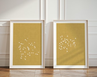 Puede incluir: Dos cuadros verticales de pared con un fondo texturizado de color amarillo mostaza y una bandada de pequeños pájaros blancos volando en formación dispersa. Cada lámina está enmarcada en madera clara con un borde limpio.