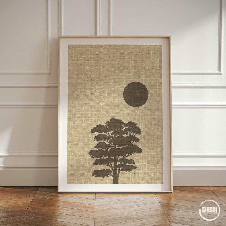 K&ouml;nnte beinhalten: Ein rechteckiger Wandkunstdruck mit der dunkelbraunen Silhouette eines Baumes und einem massiven dunkelbraunen Kreis, der die Sonne darstellt, vor einem strukturierten beigen Hintergrund. Unten rechts steht der wei&szlig;e Text SHIBUI PRINT STUDIO.