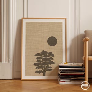 K&ouml;nnte beinhalten: Ein gerahmter rechteckiger Wandkunstdruck mit einem strukturierten beigen Hintergrund, einer dunkelgrauen Silhouette eines Baumes und einem massiven dunkelgrauen Kreis, der die Sonne oder den Mond &uuml;ber der Baumkrone im oberen rechten Quadranten darstellt.