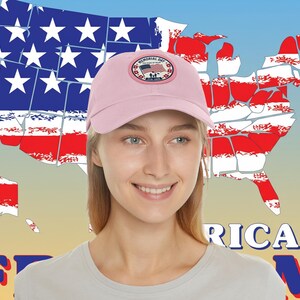 Könnte beinhalten: Eine hellrosa Baseballkappe mit einem runden Aufnäher auf der Vorderseite. Der Aufnäher zeigt eine amerikanische Flagge, den Text Memorial Day und die Jahreszahlen 1776-1976. Die Kappe hat einen gebogenen Schirm und eine strukturierte Krone.