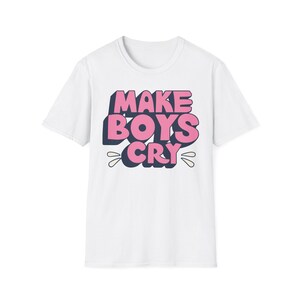 Könnte beinhalten: Weißes T-Shirt mit dem pinkfarbenen Schriftzug "MAKE BOYS CRY", umrandet in Dunkelblau. Der Text hat einen 3D-Effekt, und das Wort "CRY" hat stilisierte Tränenformen. Ein lässiges Kleidungsstück.