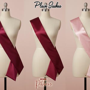 May include: Three satin sashes in burgundy and blush pink displayed on dress forms. The sashes are draped diagonally across the forms. The text "Plain Sashes" and "Wedding Ribbons" are visible in the image.
